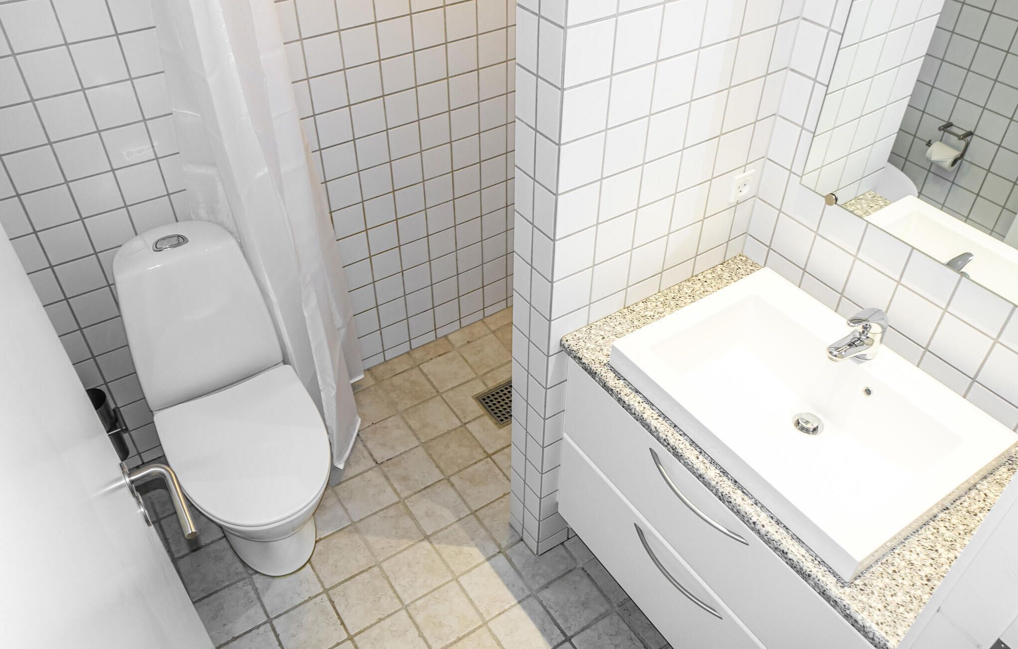A bathroom with a toilet, sink, and mirror.