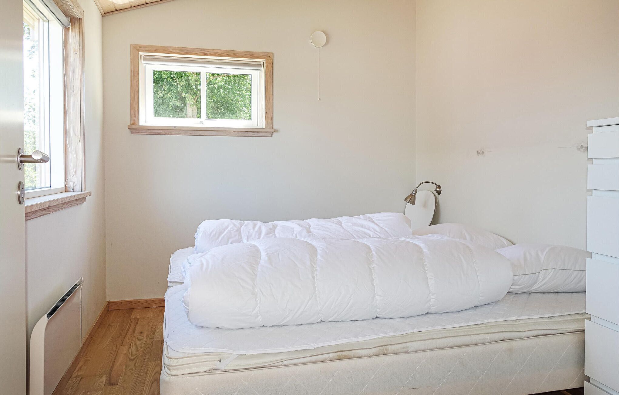 Une chambre à coucher avec un lit, une fenêtre, un radiateur et une lampe fixée au mur.