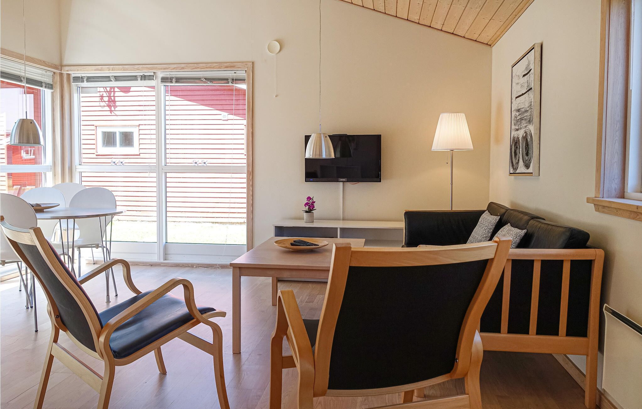 Una sala de estar con un sofá, dos sillones, una mesa, un televisor y una lámpara.