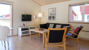 Un salon moderne avec un téléviseur à écran plat, un canapé, une table à manger et une chaise.