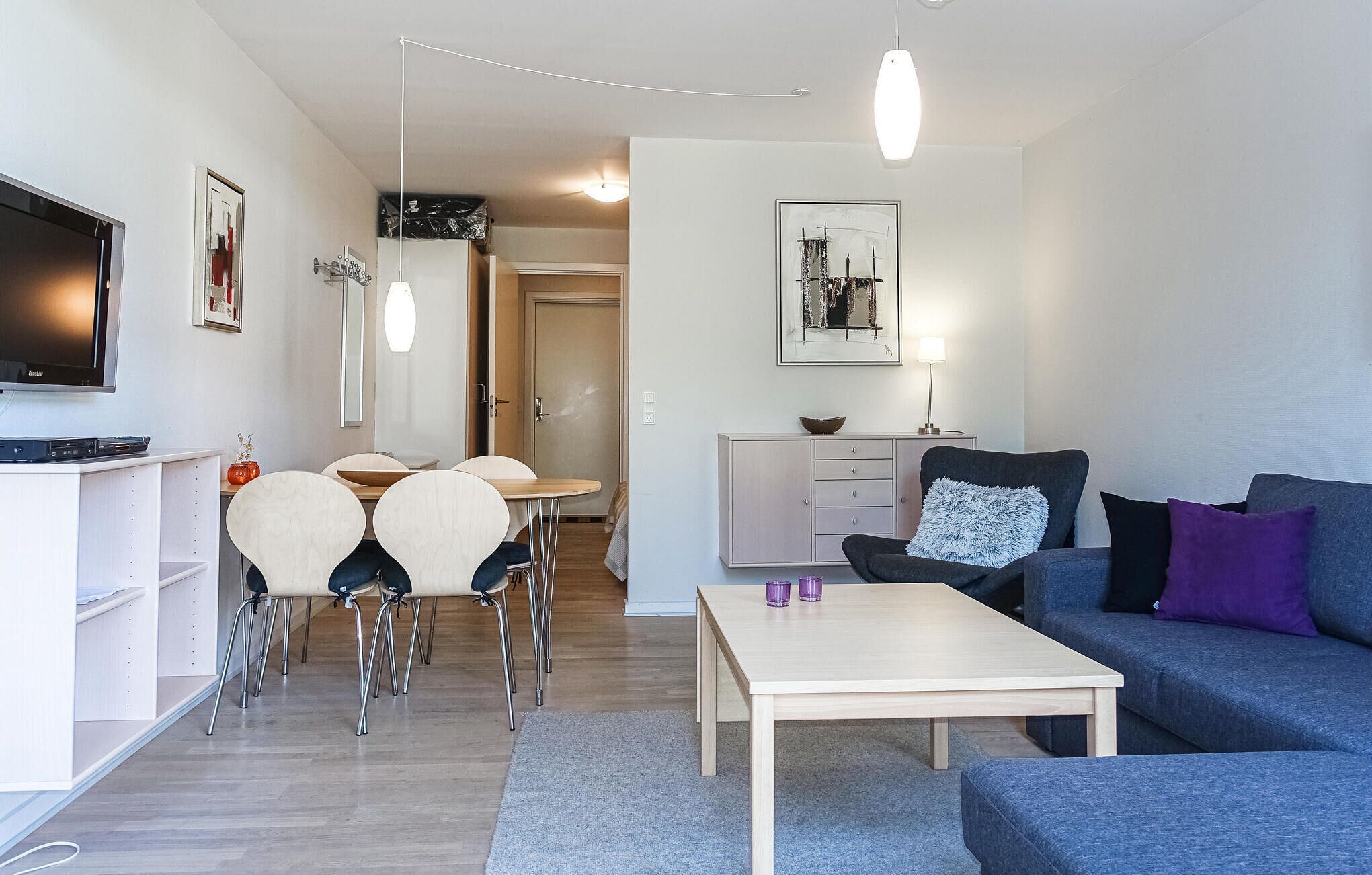 A modern living room with a TV, dining area, and seating.