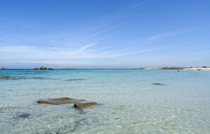 Une plage dégagée, avec des rochers visibles et une eau calme.