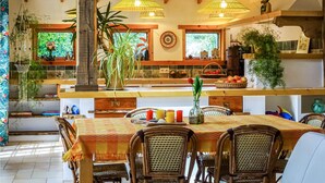 A cozy kitchen with wooden beams, a dining table with chairs, and hanging pendant lights. - 2 bedroom nice home in Plouguerneau (Plouguerneau)