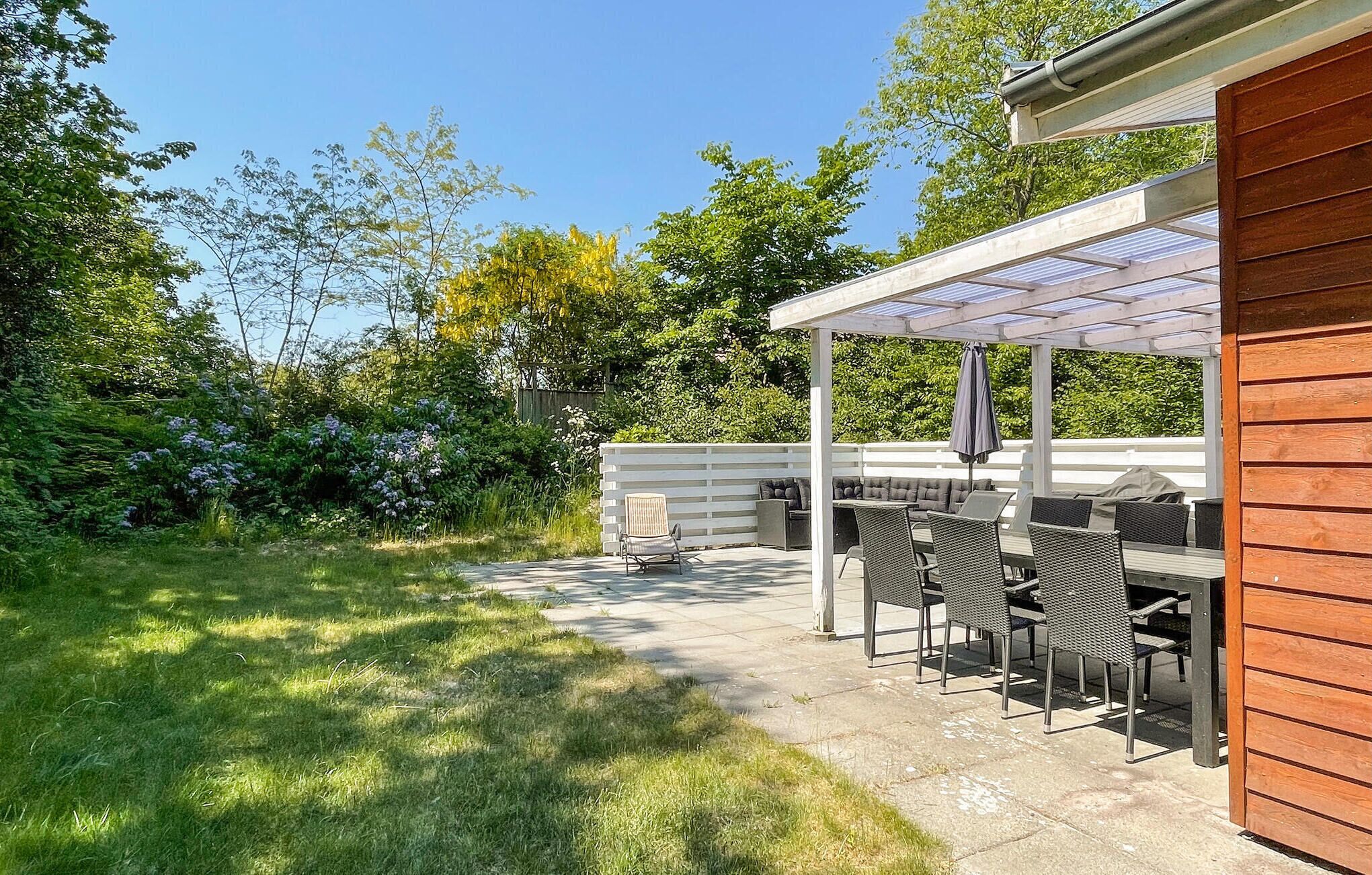 An outdoor patio with a covered seating area, a grill, and a wooden fence.