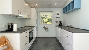 Una cucina moderna con mobili bianchi, un piano di lavoro nero e una finestra vista verde.