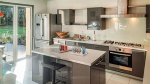 A modern kitchen with stainless steel appliances, a central island with bar stools, and a view of the outdoors. - 3 bedroom awesome home in Moelan sur Mer (Moelan sur Mer)