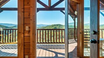 A wooden deck with a view of green hills and mountains.