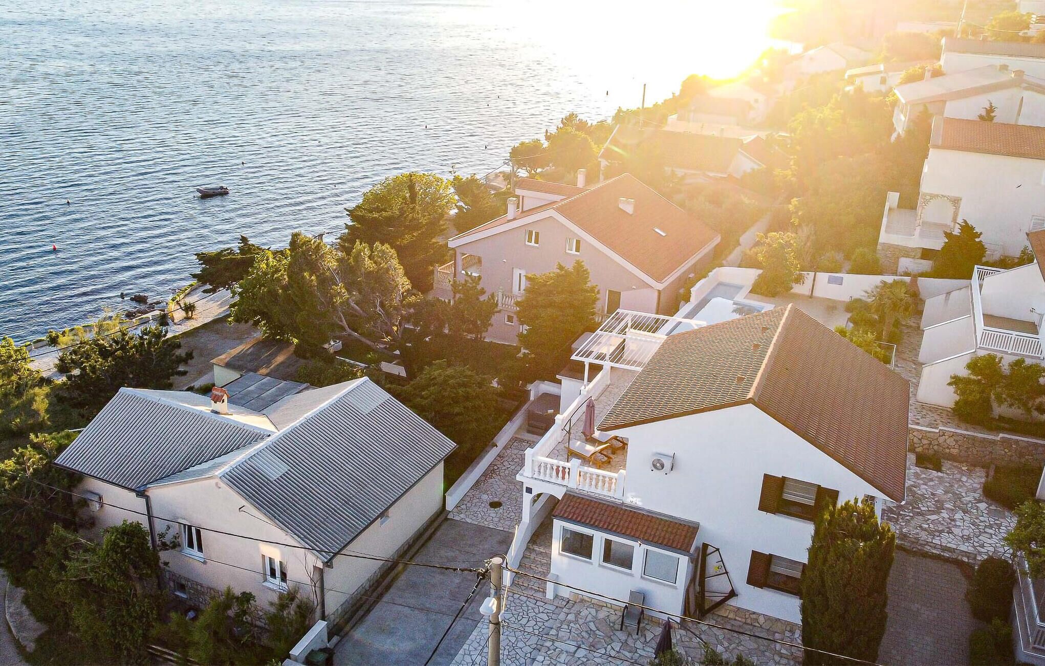 Et kystnære boligområde med huse, fri udsigt til havet og en solnedgang.