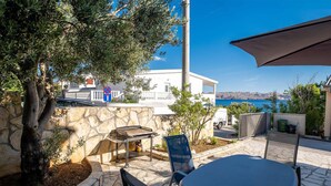 Un patio con mesa y sillas, una parrilla y vistas al mar y a las montañas.