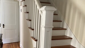 A staircase with white balusters and wooden steps, leading to a landing with a door.