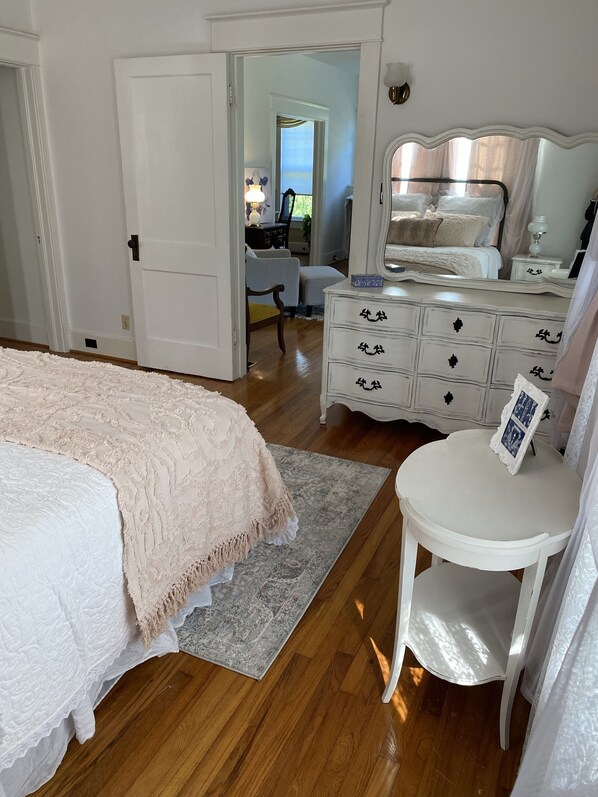 Un dormitorio con una cama grande, un tocador, una silla y un escritorio.