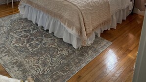 A bedroom with a bed, a bedside table, a lamp, and a rug.