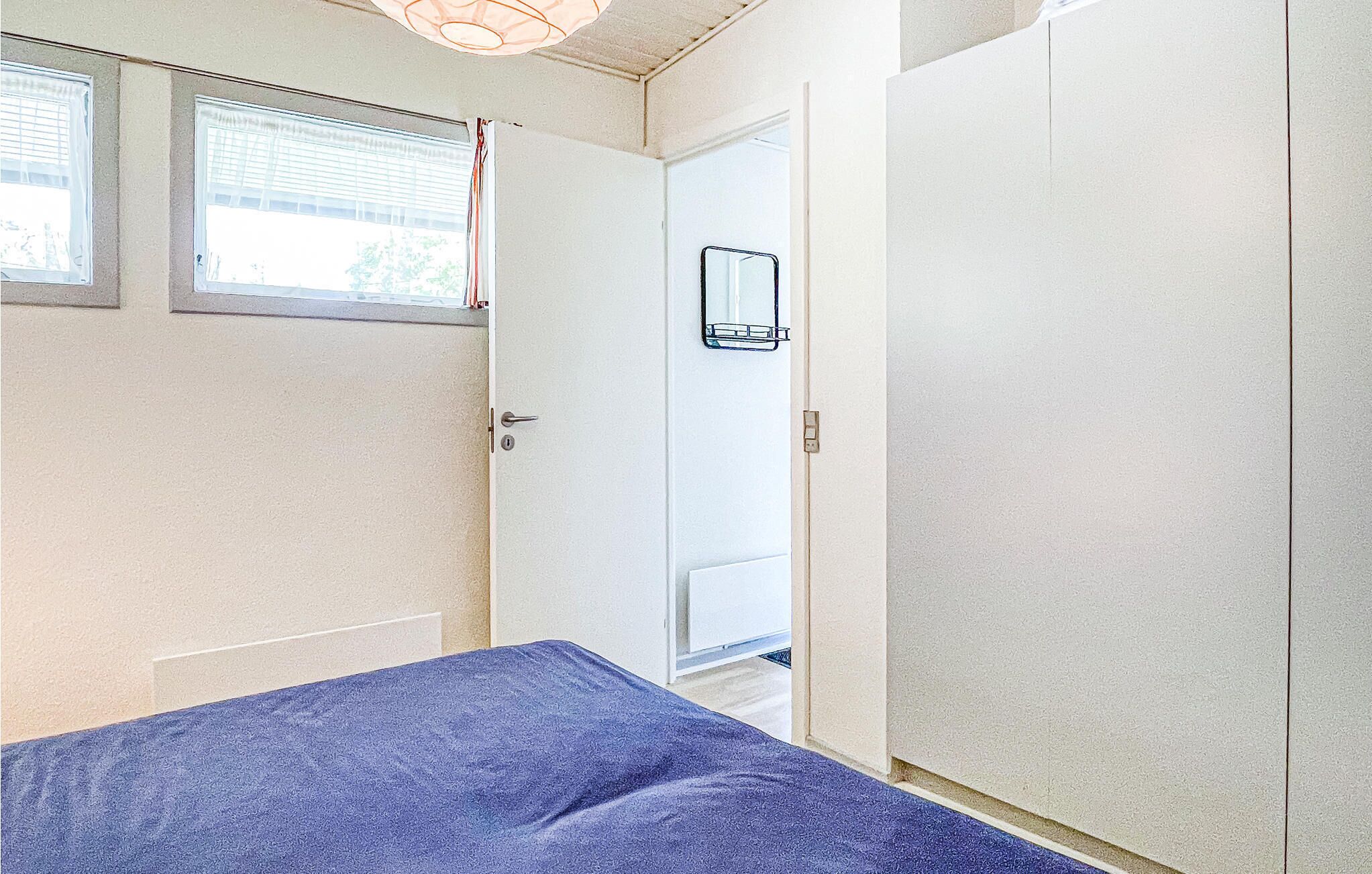 A bedroom with a bed, a door, and a window.