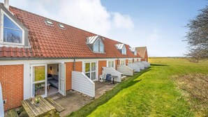 Une rangée de maisons de plain-pied, avec des toits recouverts de tuiles rouges, de grandes fenêtres et des vérandas attenantes.