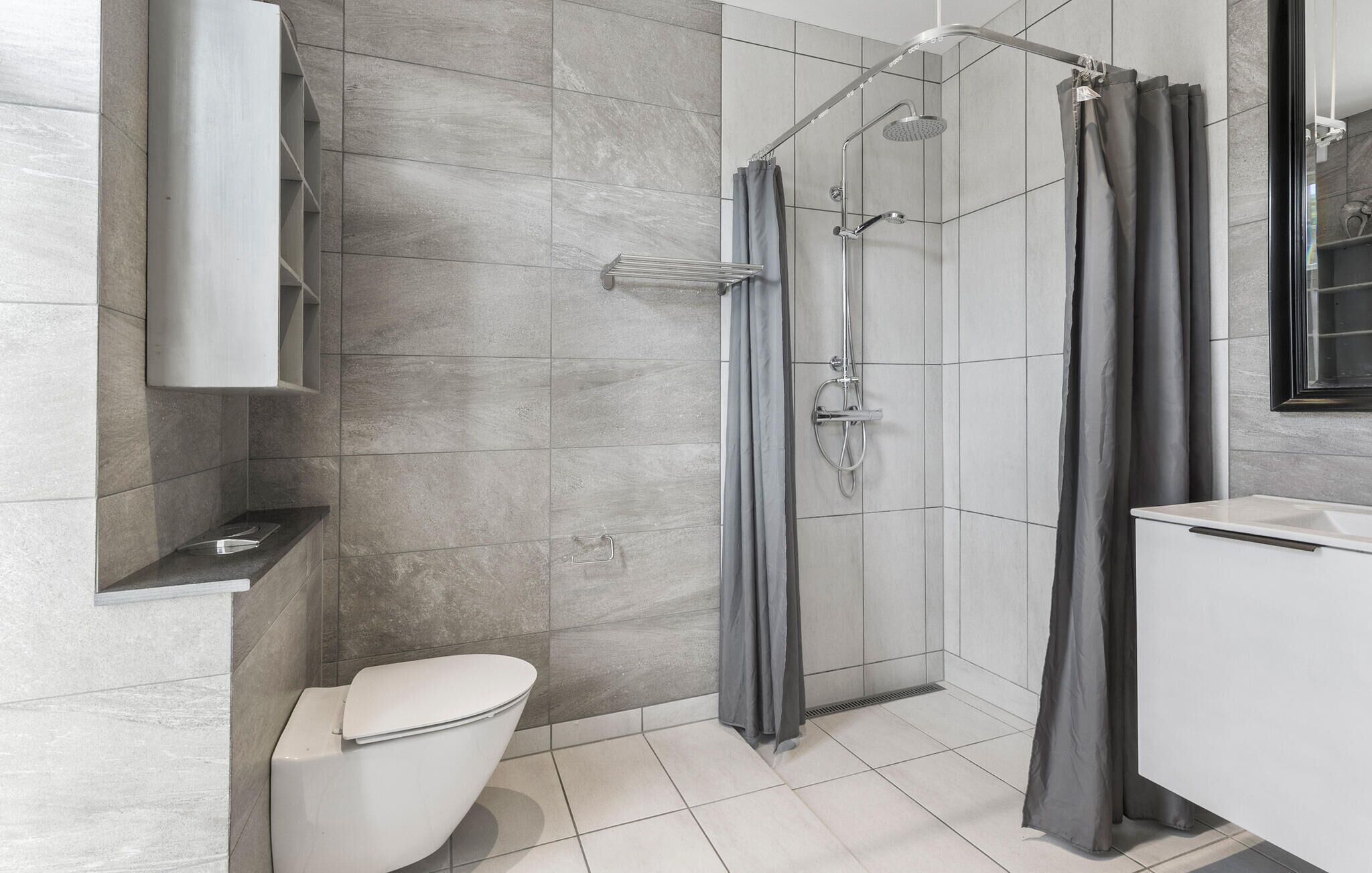 A modern bathroom with a shower, toilet, and sink.