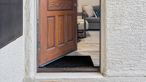A wooden door with a decorative panel and a welcome mat with cacti. - Sonoran Style 2BR/2BA w. Free Parking & Pool (Scottsdale)
