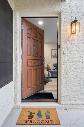 A wooden door with a decorative panel and a welcome mat with cacti. - Sonoran Style 2BR/2BA w. Free Parking & Pool (Scottsdale)