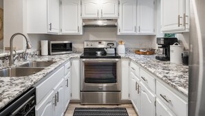 A modern kitchen with white cabinets, stainless steel appliances, and a granite countertop. - Sonoran Style 2BR/2BA w. Free Parking & Pool (Scottsdale)