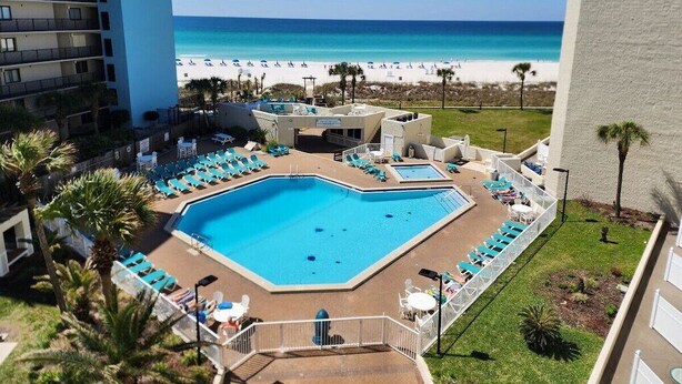 A hotel pool area with multiple swimming pools, lounge chairs, and a view of the beach. - Tootsie's Next Door! Top of The Gulf! (Panama City Beach)