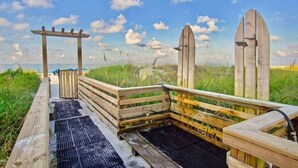 A wooden deck with a metal grill, a wooden pergola, and a view of the beach. - Tootsie's Next Door! Top of The Gulf! (Panama City Beach)