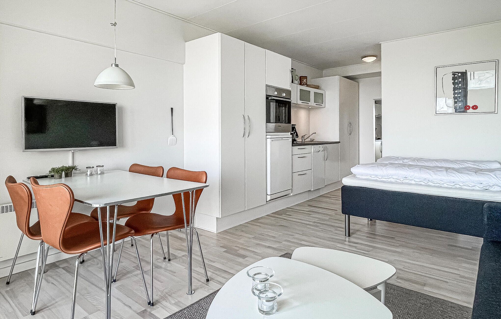 Ein modernes, kleines Hotelzimmer mit Essbereich, Küchenzeile und einem Bett.