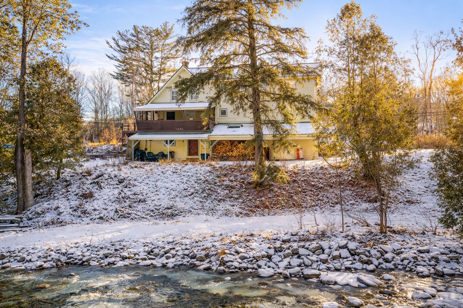 A two-story house with a porch and a river in front.