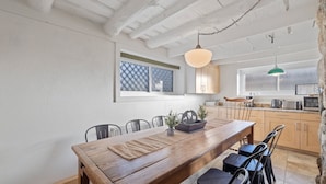 A dining area with a wooden table, chairs, and a hanging light fixture.