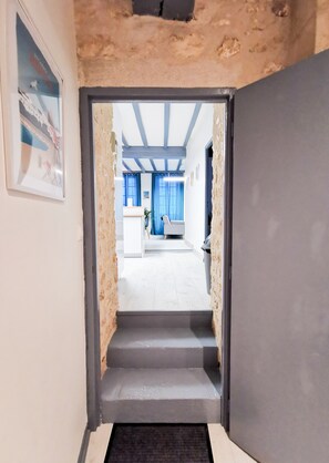Stairs lead to a room with a minimalist design, featuring a framed picture and a door.