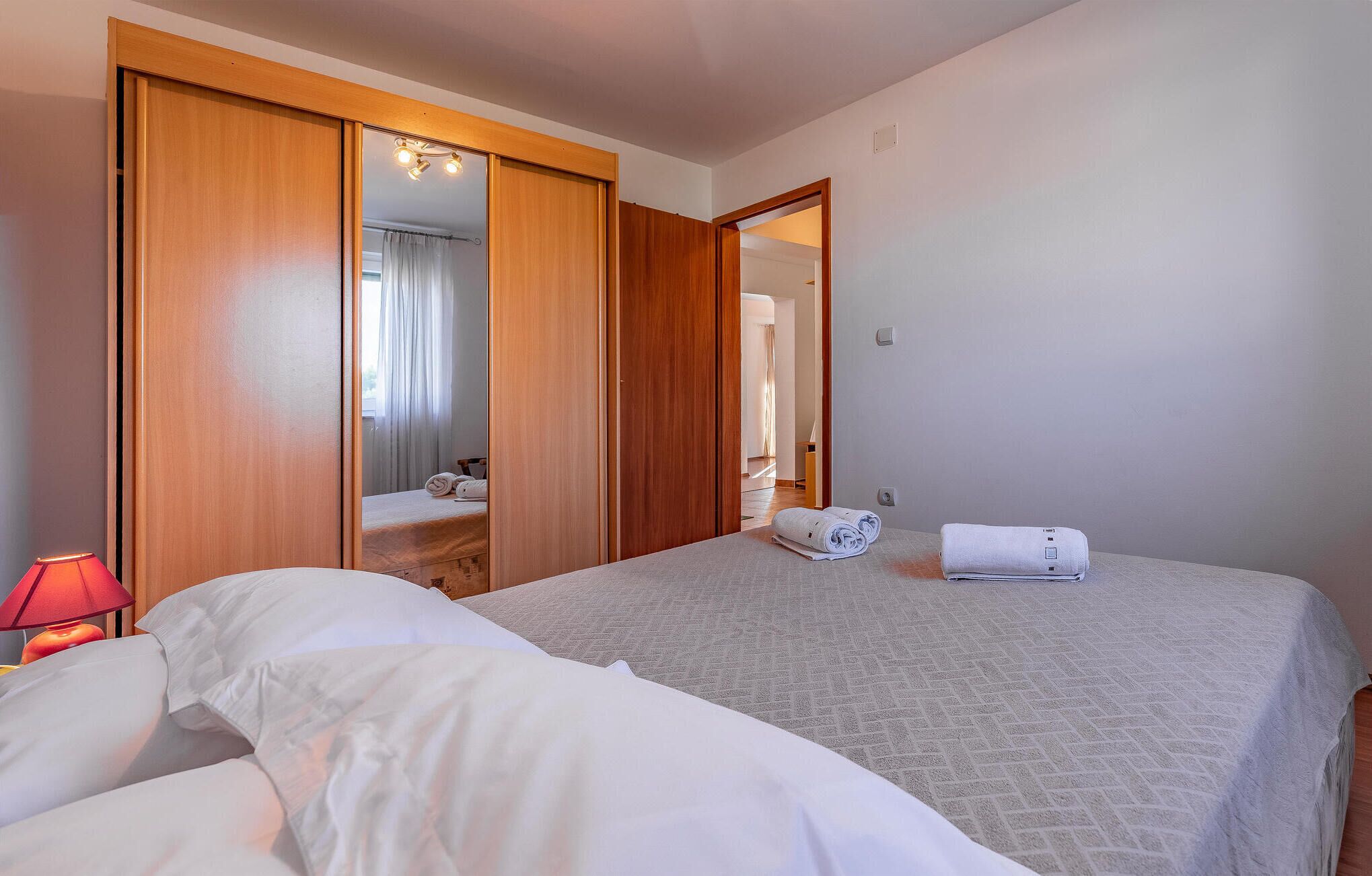 Ein Hotelzimmer mit zwei Betten, einem Holzschrank, einem Spiegel und einer roten Lampe.