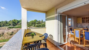 Ein Balkon mit Tisch und Stühlen, einem Blumentopf und Blick auf einen Hügel mit Bäumen.