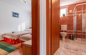 Een slaapkamer met een bed, een badkamer met toilet en douche, en een gang.