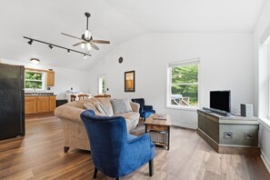 Una sala de estar moderna con un sofá, un sillón azul, un televisor y una mesa de centro de madera.
