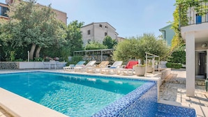 A swimming pool with tiled edges, lounge chairs, and a covered area with a pergola. - 1 bedroom nice apartment in Banjole (Banjole)