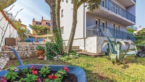 A residential building with a stone facade, a balcony, and a garden with potted plants and flowers. - 1 bedroom nice apartment in Banjole (Banjole)