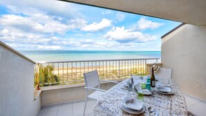 A balcony with a table set for dining, overlooking a beach and the sea. - Nice apartment in Alcamo Marina with WiFi (Alcamo Marina)