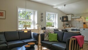 A modern living room with a sofa set, a coffee table, and a dining area with a kitchen in the background.