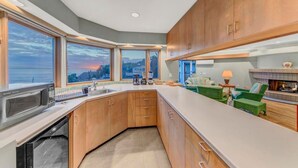 A modern kitchen with wooden cabinets, a built-in oven, and a large window offering a scenic view. - Oceanfront 4 bedroom villa w/ 2 masters and views (Encinitas)