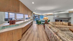 A modern kitchen with a large island, a dining area with a sofa, and a fireplace. - Oceanfront 4 bedroom villa w/ 2 masters and views (Encinitas)