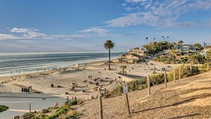 A coastal beach area with a sandy beach, a palm tree, and a residential area with houses and greenery. - Oceanfront 4 bedroom villa w/ 2 masters and views (Encinitas)