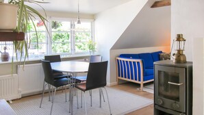 Un accogliente soggiorno con zona pranzo, un divano blu e una stufa a legna.