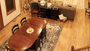 Un amplio salón con chimenea, vigas de madera y una mesa de comedor con sillas.