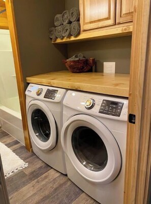 Convenient laundry area with two front-loading washing machines and a storage platform.