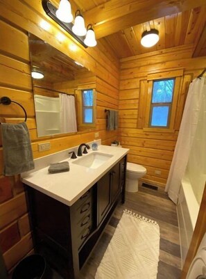 A wooden cabin bathroom with a sink, mirror, and toilet.