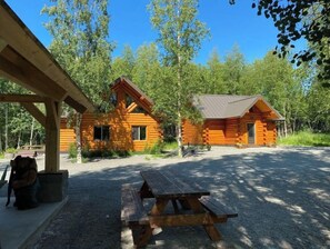 A rustic cabin with a covered porch and a picnic table in front.
