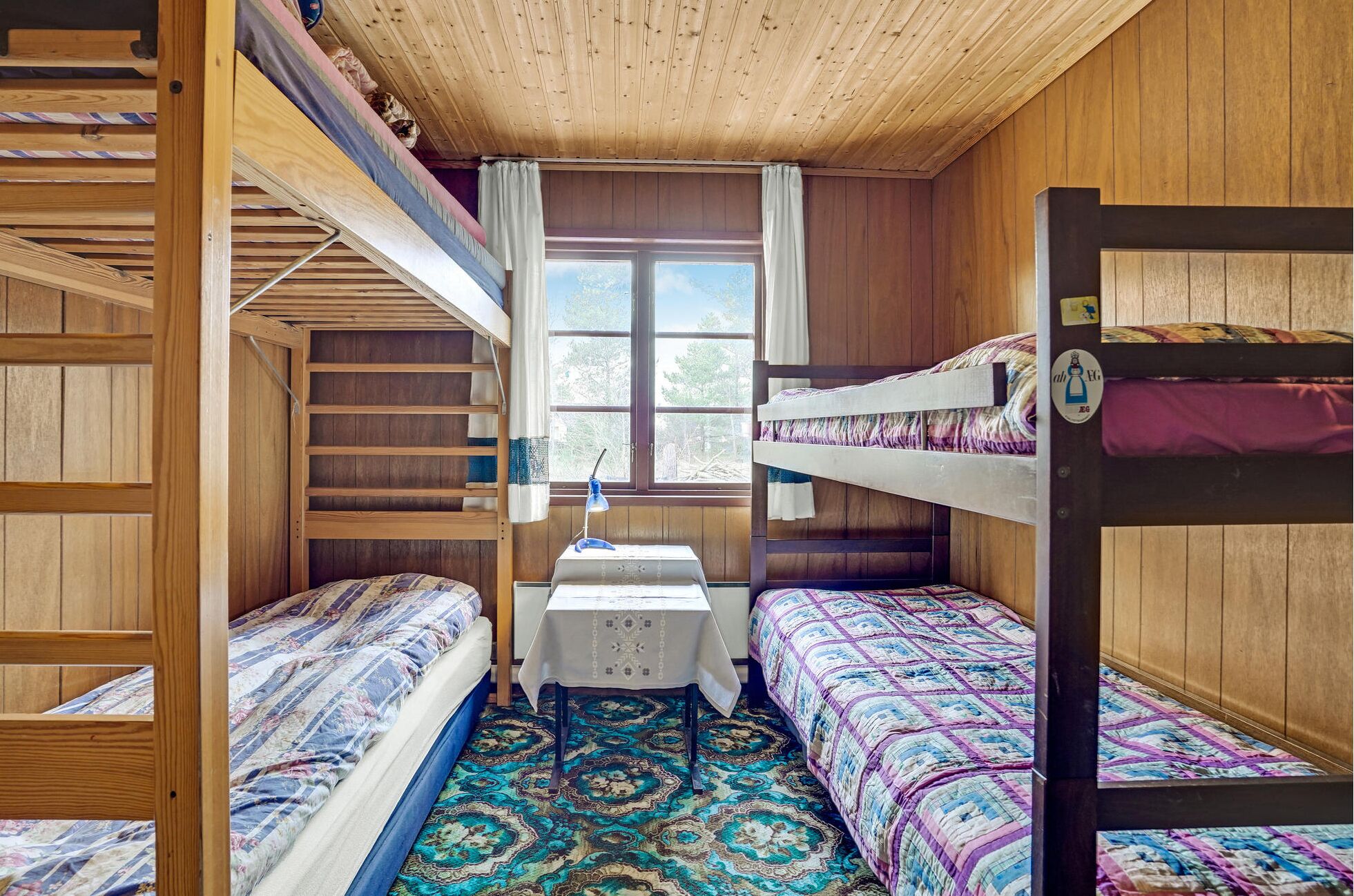 A compact room with bunk beds, a small table, and a patterned carpet.