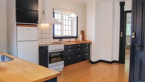 A kitchen with a stove, oven, and sink. There is a window with curtains and a door with a handle. - Amazing home in Gudhjem with house sea view (Gudhjem)