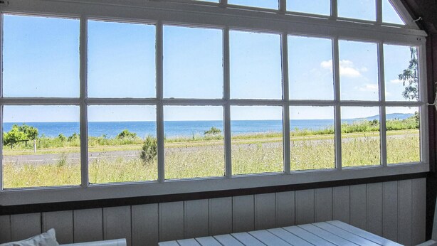 A room with a large window offering a view of the sea and fields. - Amazing home in Gudhjem with house sea view (Gudhjem)
