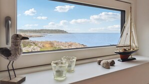 Ein Fenster mit Blick auf eine felsige Küste und einem Modell eines Segelboots auf der Fensterbank.