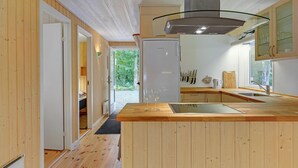 Une cuisine moderne avec un lambris en bois, une cuisinière encastrée et une grande fenêtre offrant une vue sur l’extérieur.