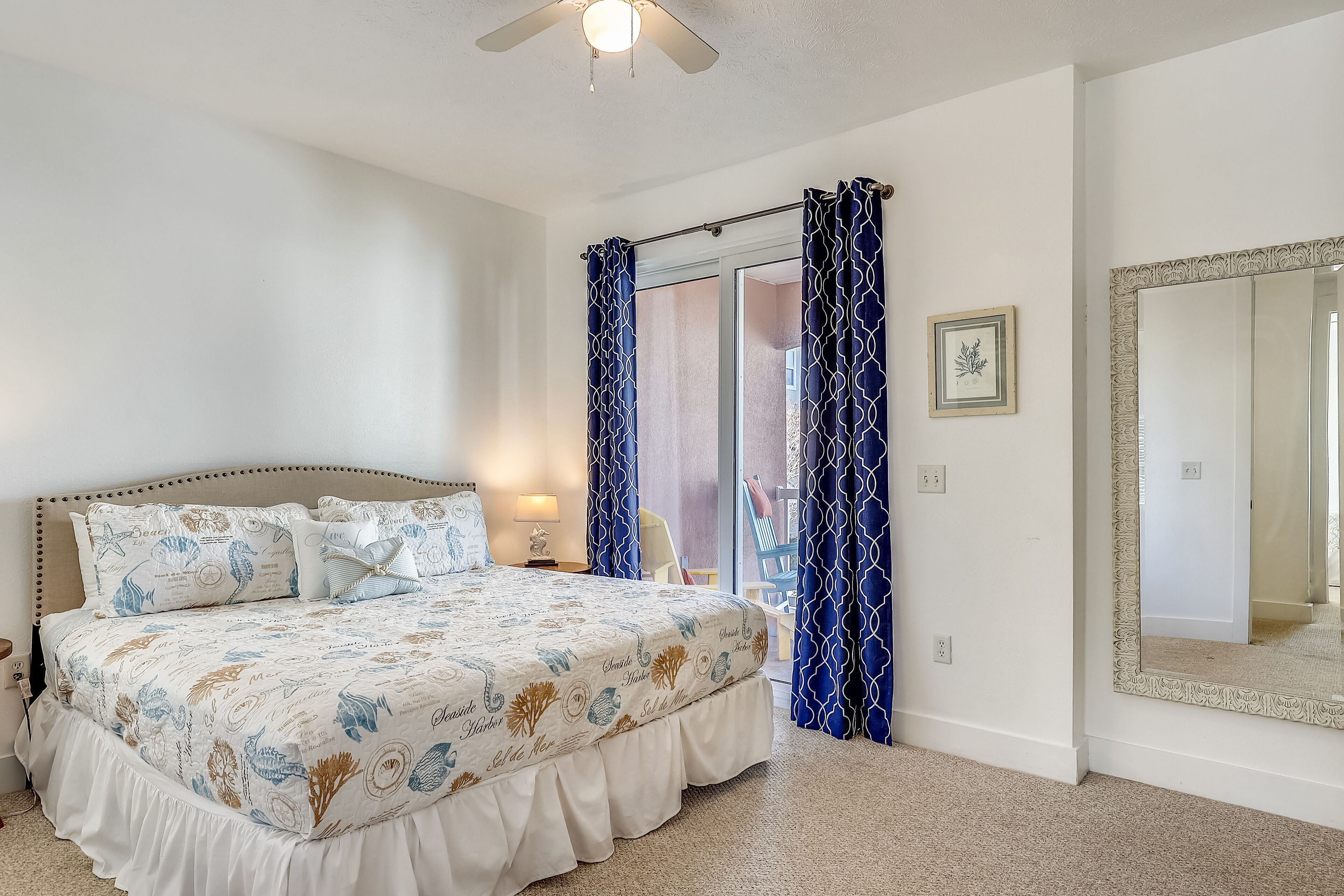 Quarto com cama, cortinas, um espelho e vista para o exterior.